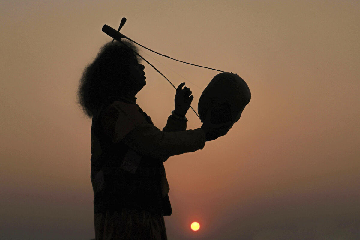 A folk singer performs against the backdrop of the setting sun, in Birbhum