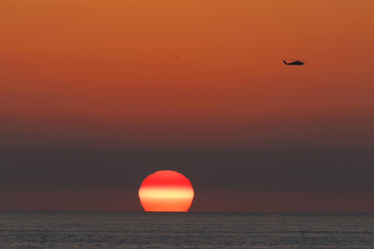 A US military helicopter flies past as the sun sets in Encinitas, California