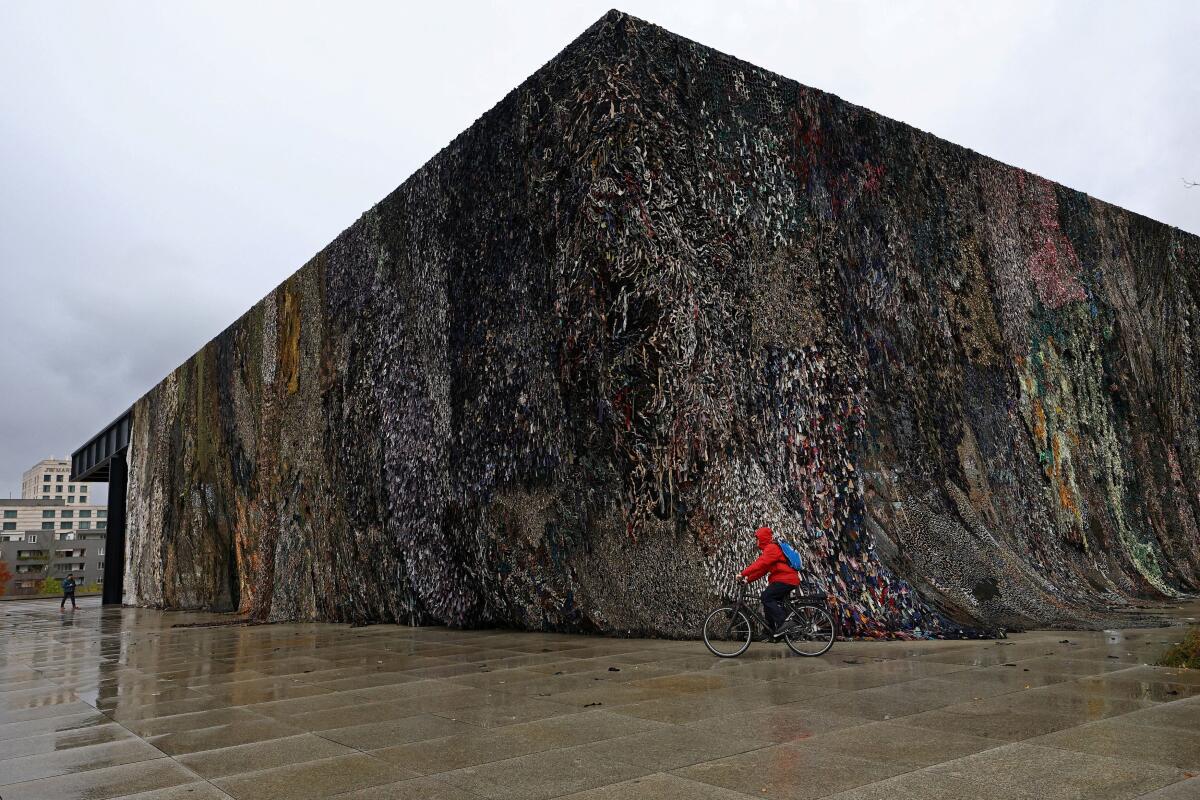 A cyclist rides his bike in front of the artwork "Laughing is suspicious”, an installation by artist Fabian Knecht during the preview of the exhibition "Festival of Future Nows 2025" at Neue Nationalgalerie museum in Berlin, Germany