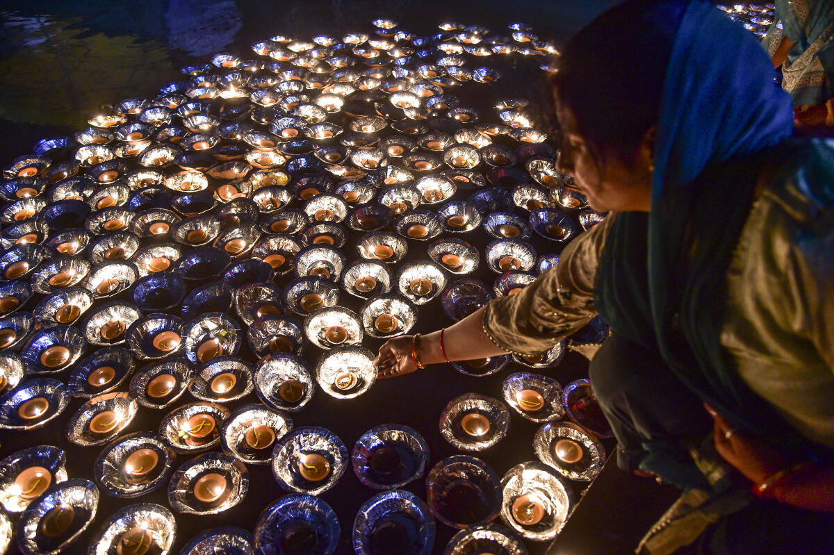A woman lights earthen lamps at Mauj Giri ghat along the banks of Yamuna river as part of 'Kalindi Mahotsav' celebrations, in Prayagraj, Uttar Pradesh