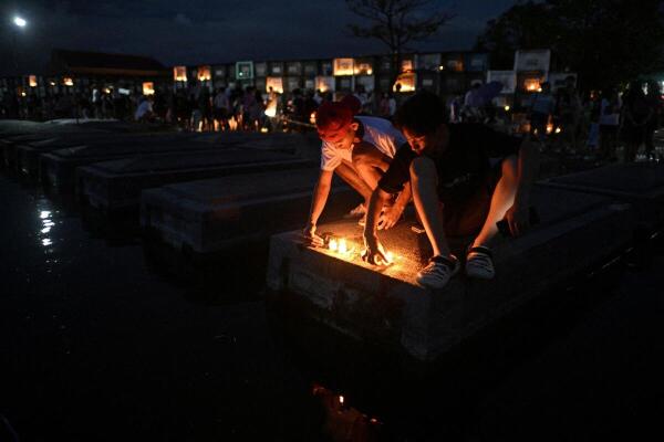 People light candles on the tomb of a deceased loved one during All Saints' Day at a flooded cemetery in Masantol, Pampanga, Philippines.