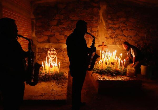A man lights candles at the grave of his loved one while musicians play during the Day of the Dead festivities, in Mazatlan Villa de Flores, Mexico.