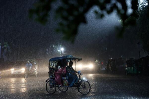 A rickshaw moves on the street during a downpour in Dhaka, Bangladesh.