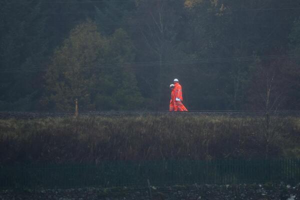 Rail workers walk along the track near the site of a train derailment near Shap in Cumbria, Britain.