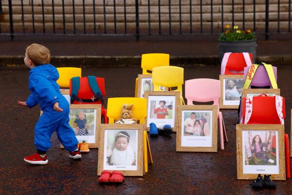 A toddler runs past a demonstration featuring pictures of slain children from Gaza placed next to children's school chairs, outside Stormont parliament building as parties back a motion for no confidence in Minister for Education from the DUP party, Paul Givan, over his recent visit to Israel, in Belfast, Northern Ireland.