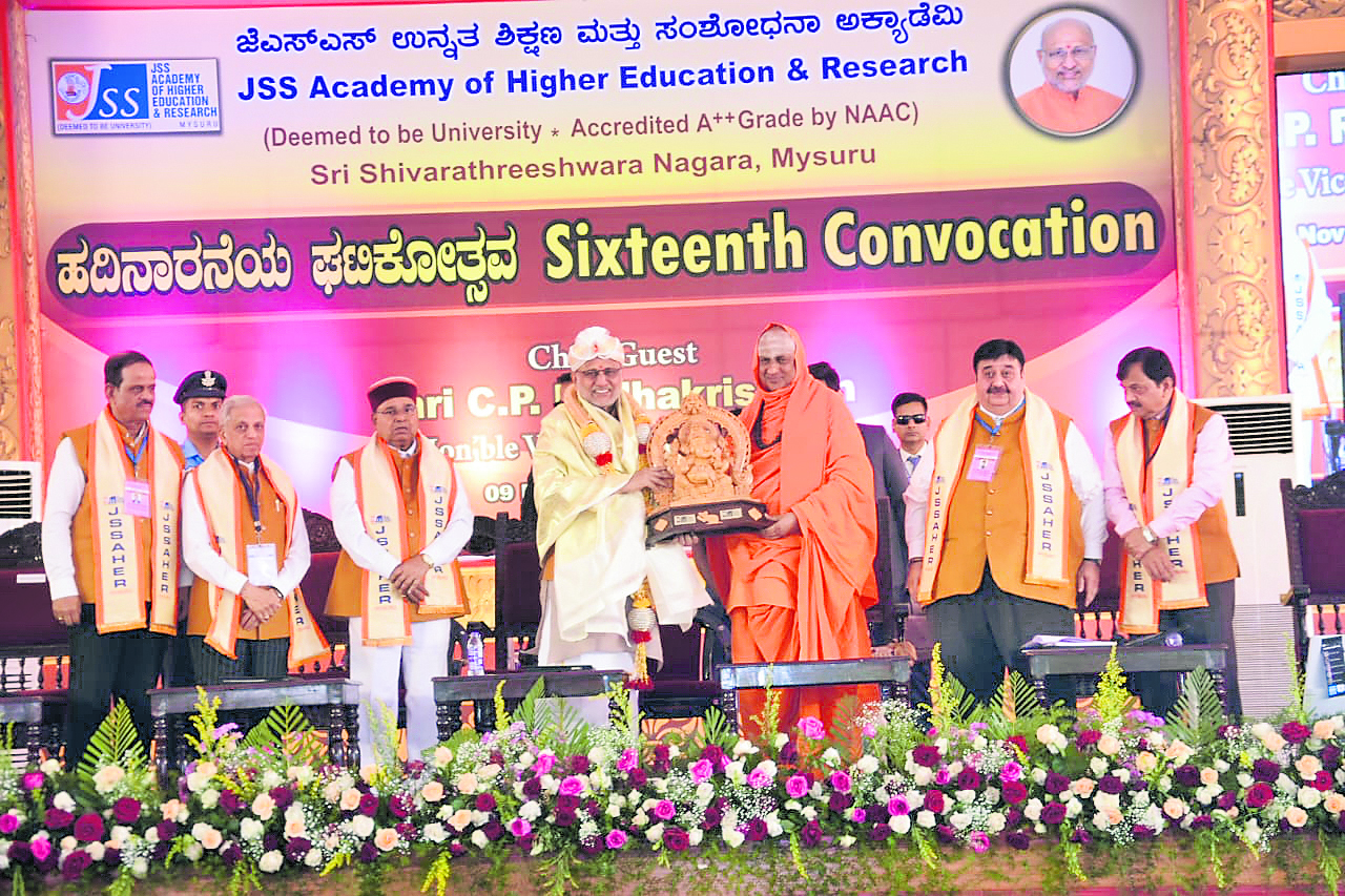 Vice President of India C P Radhakrishnan receives Ganesha idol from Suttur Mutt Seer Shivarathri Deshikendra Swami at the sixteenth convocation of JSS Academy of Higher Education and Research in Mysuru on Sunday. Governor Thaawarchand Gehlot is also seen. Credit: DH Photo