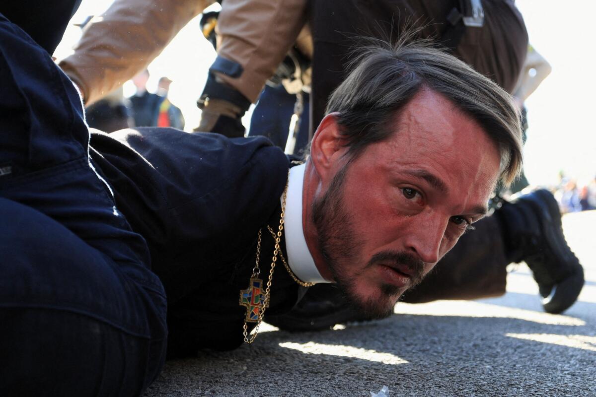 A faith leader is detained by Illinois State Police during a protest against immigration actions, outside the Broadview ICE facility in Chicago, Illinois, U.S.