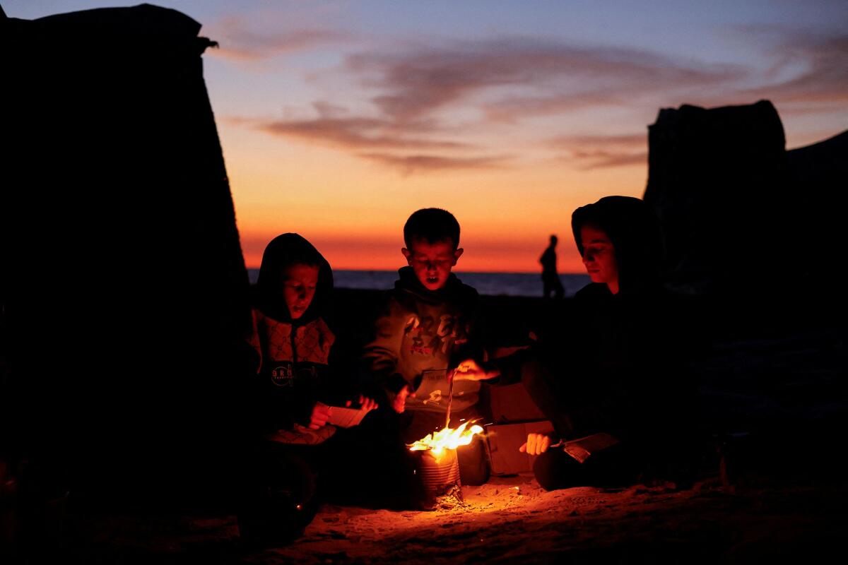Palestinian children sit next to a fire, amid a ceasefire between Israel and Hamas, in central Gaza Strip.