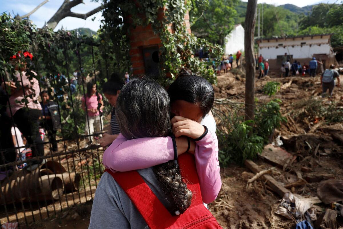 People react while standing at an area damaged by a landslide after six hours of torrential rain that destroyed homes and left people missing, in Achira, Santa Cruz, Bolivia.