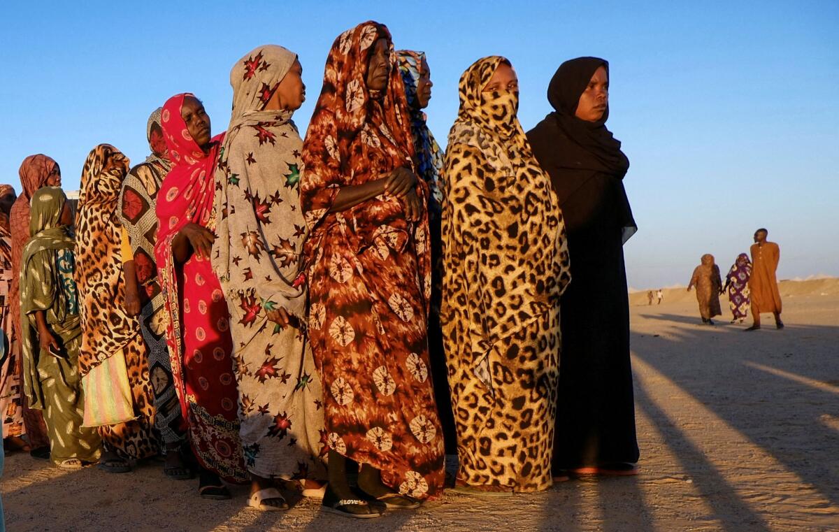 Displaced women stand in line as they wait for their turn to receive aid, at a displacement camp in Al-Dabba, Sudan.