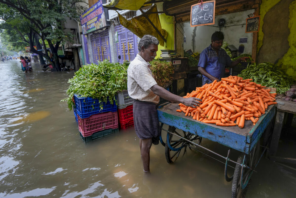 A man shops for vegetable on a waterlogged street following Cyclone Ditwah, in Chennai