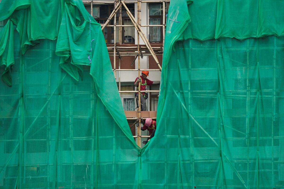 Workers remove scaffolding mesh from a building at Sui Wo Court in Sha Tin, following authorities' decision to remove the netting amid investigations into a deadly fire at Wang Fuk Court, in Hong Kong, China