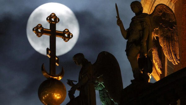 The moon rises behind statues of angels decorating St Isaac's Cathedral in Saint Petersburg, Russia.
