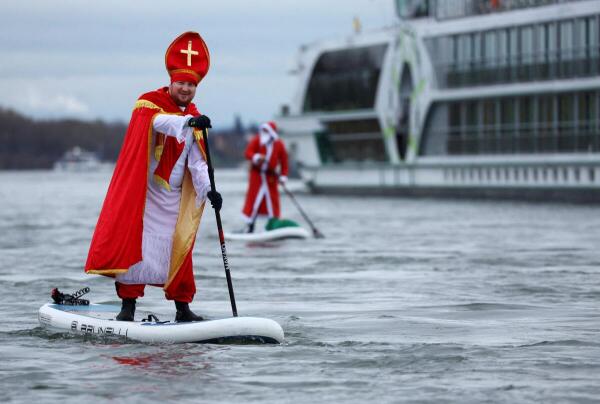 People dressed as Santa Claus ride stand-up paddle boards on the Rhine river.