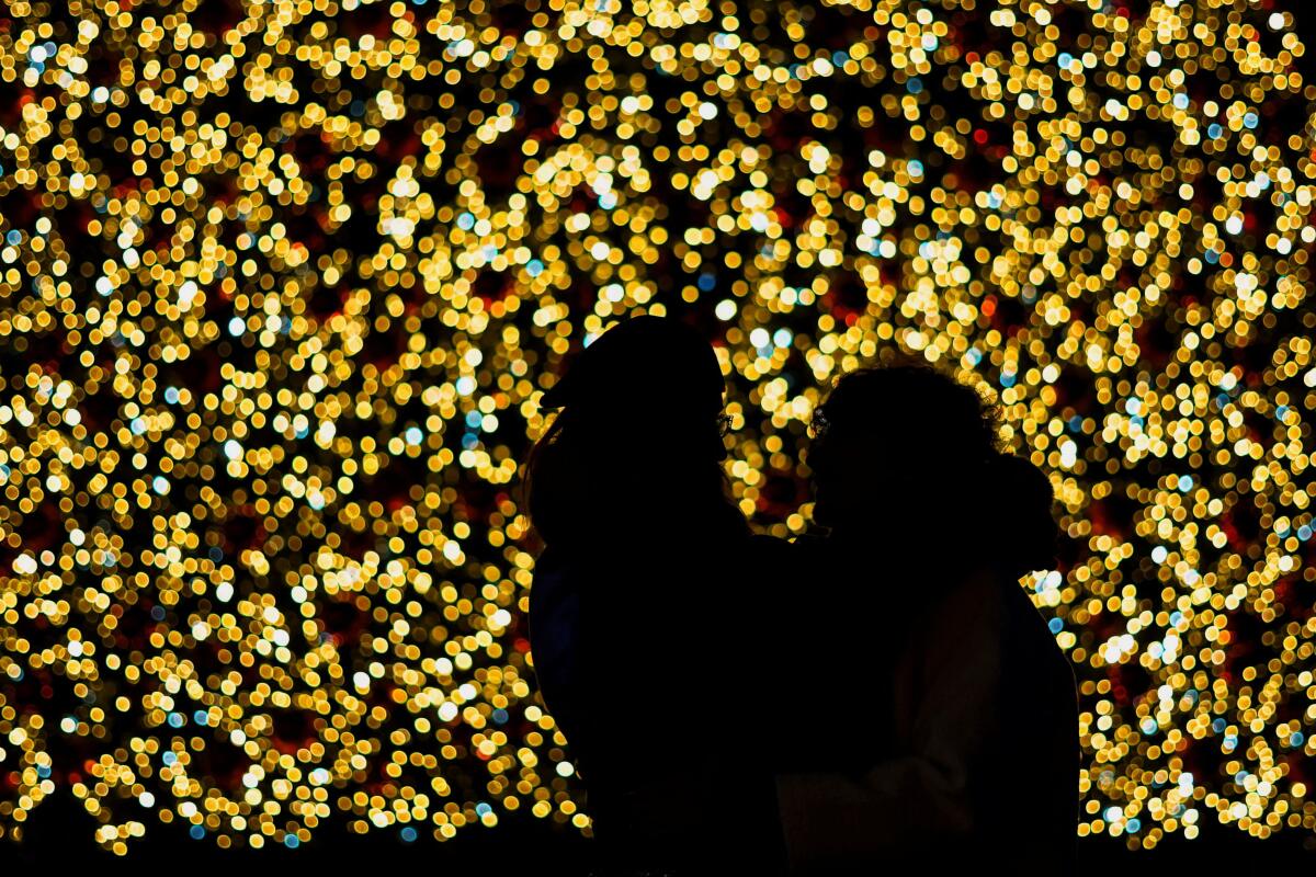 Two people pose in front of a Christmas tree installed in Puerta del Sol in Madrid, Spain.