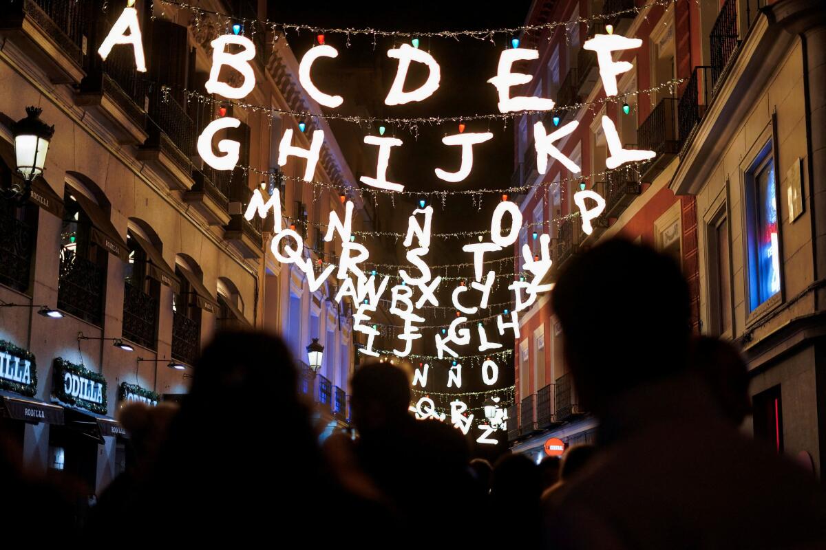 People walk along Postigo de San Martin street decorated with Christmas lights, inspired by the Netflix's TV show Stranger Things in Madrid, Spain.