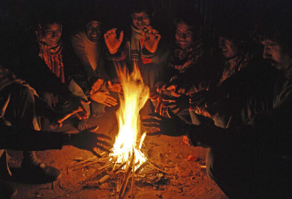 People warm themselves around a small fire on a winter evening, in Birbhum district, West Bengal.
