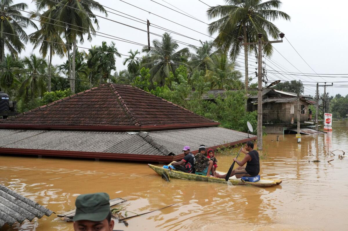 People ride in a boat in a flooded area, following heavy rainfall in Malwana.