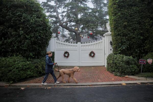 A woman walks her dog outside the Reiner household, where actor-director and political activist Rob Reiner and his wife were found dead, in Los Angeles, California, US.