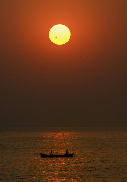 Fishermen row a boat during sunset, in Mumbai