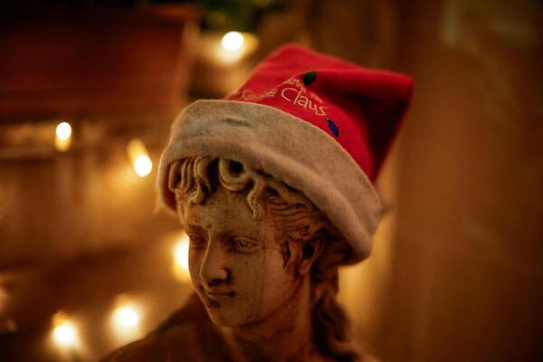 A statue with a Santa Claus hat outside a house decorated with Christmas lights in Nadur on the island of Gozo, Malta.