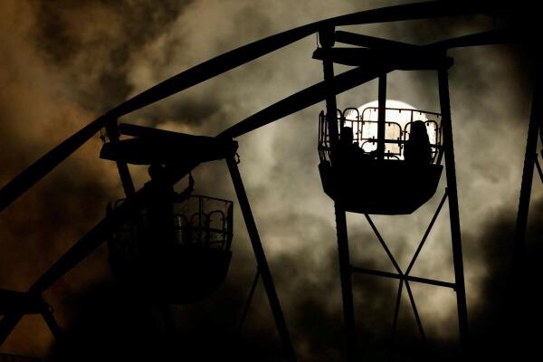 People ride on a ferris wheel at the Fairyland Malta Christmas Village as the sun is partly hidden behind clouds in Valletta, Malta.