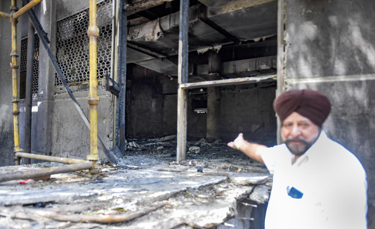 A man shows charred remains after a fire at Uphaar Cinema, which has been shut since 1997 following a blaze that killed 59 people, in New Delhi.