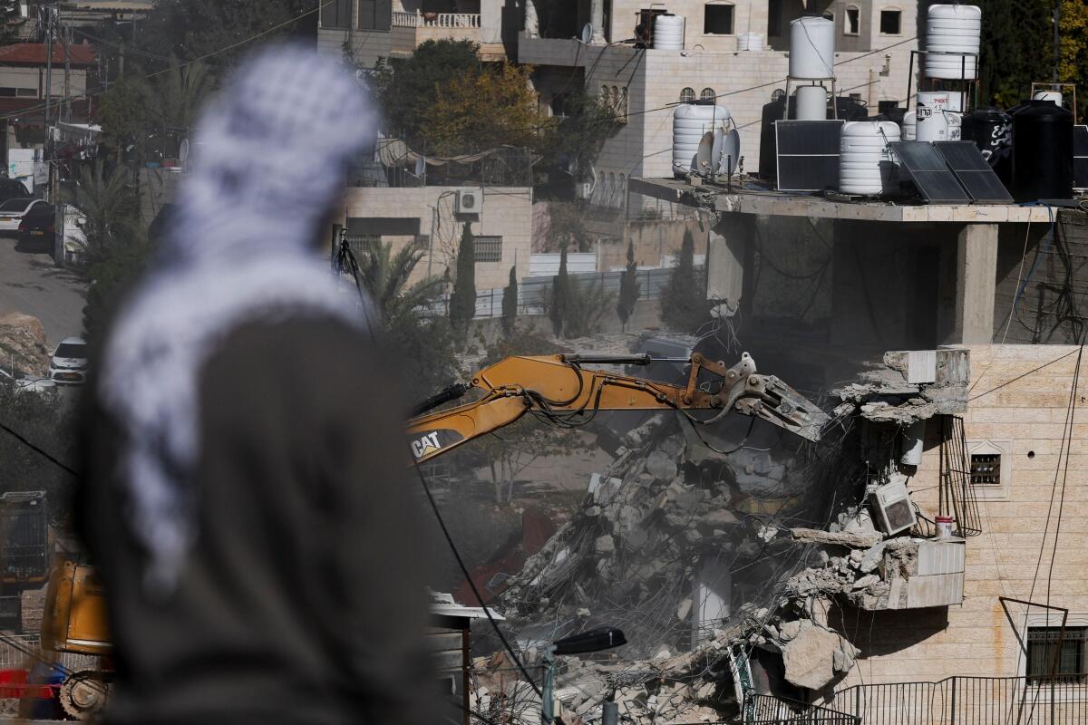 A man watches as Israeli forces demolish a residential building where Palestinian families lived, near the Silwan neighbourhood of East Jerusalem.