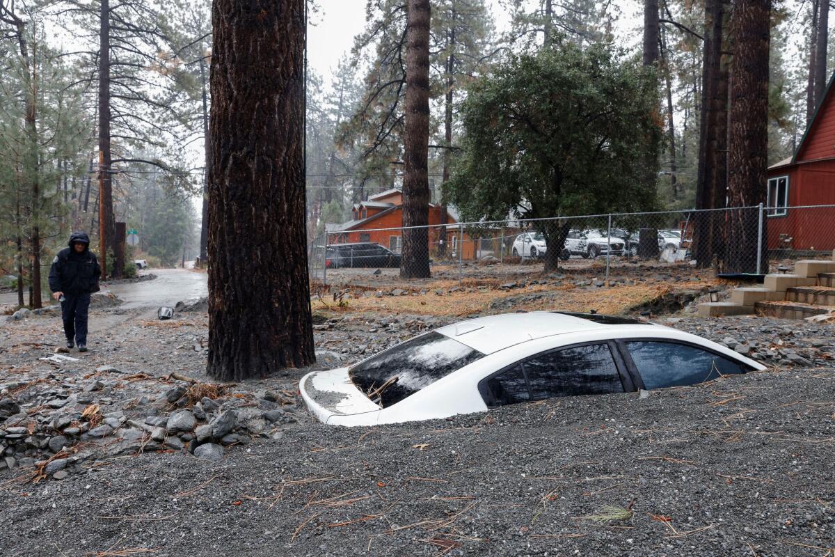 Ryan Beckers, Public Information Officer for San Bernardino County Fire Protection District, walks near a partially buried car as heavy rains fall due to an atmospheric river, in Wrightwood, California, US.