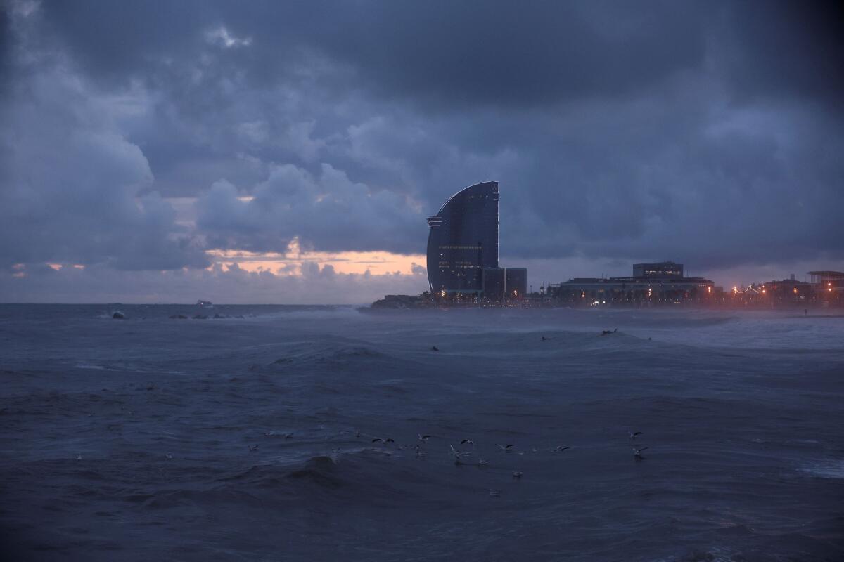 Surfers swim on La Barceloneta Beach as a passing storm hits Barcelona, Spain.