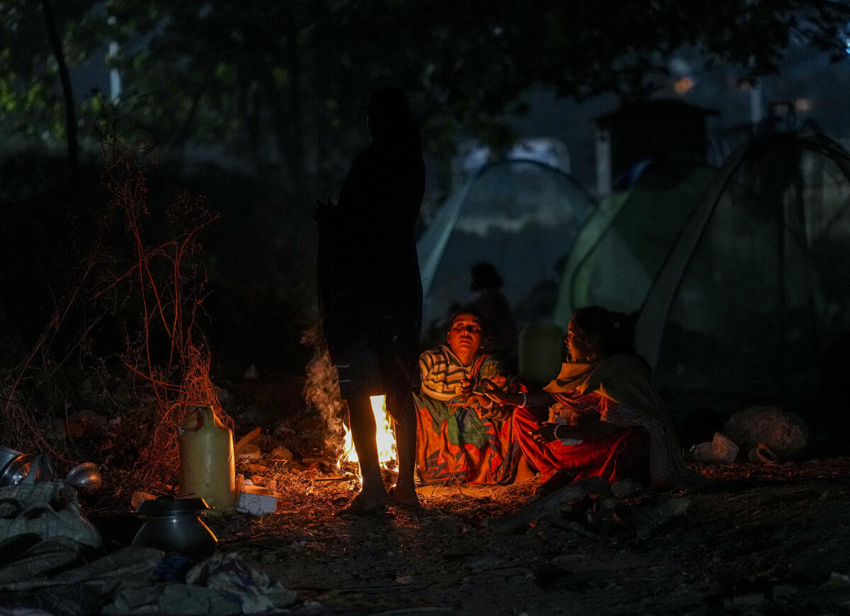 People sit around a small fire as temperatures drop during winter, in Kolkata.