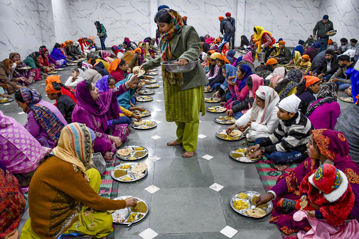 People receive free food at a ‘langar’, community kitchen, on the birth anniversary of the 10th Sikh Guru, Guru Gobind Singh, at a gurudwara, in Prayagraj.