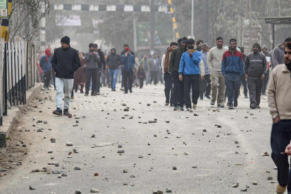 People walk down a road covered with stones pelted by protesters amid an agitation by locals against the Supreme Court's order regarding the leasing of 2,866 acres of government forest land, in Rishikesh, Dehradun district, Uttarakhand.