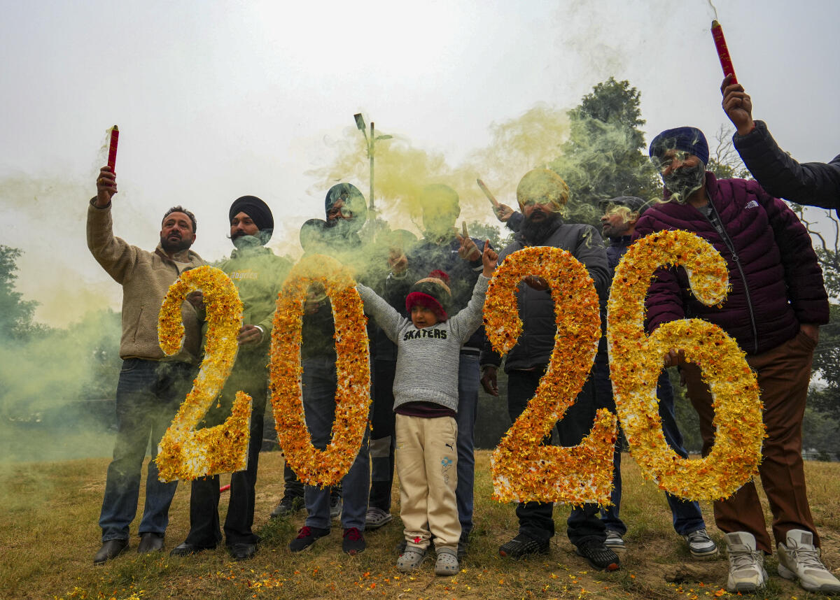 People pose for a picture holding '2026' cut-outs on New Year’s eve, in Amritsar, Wednesday, Dec. 31, 2025.