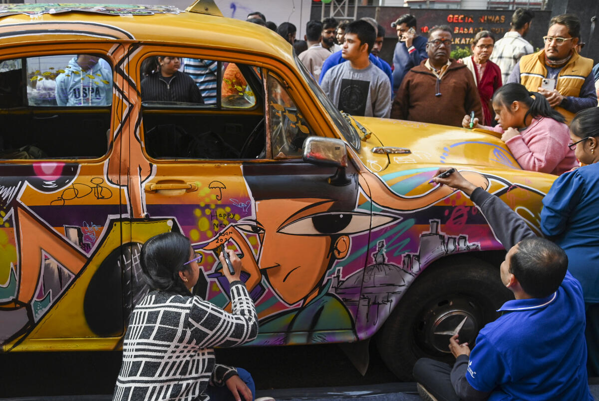 Specially-abled children paint a taxi during the 'Caravan Winter Carnival' on the first day of 2026, in Kolkata, Thursday, Jan. 1, 2026.