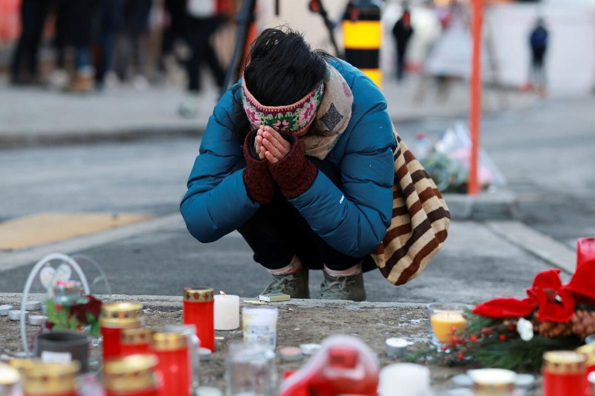 A person pays tribute next to the candles placed for the victims outside the "Le Constellation" bar, after a fire and explosion during a New Year's Eve party where several people died and others were injured, according to Swiss police, in the upscale ski resort of Crans-Montana in southwestern Switzerland, January 2, 2026.