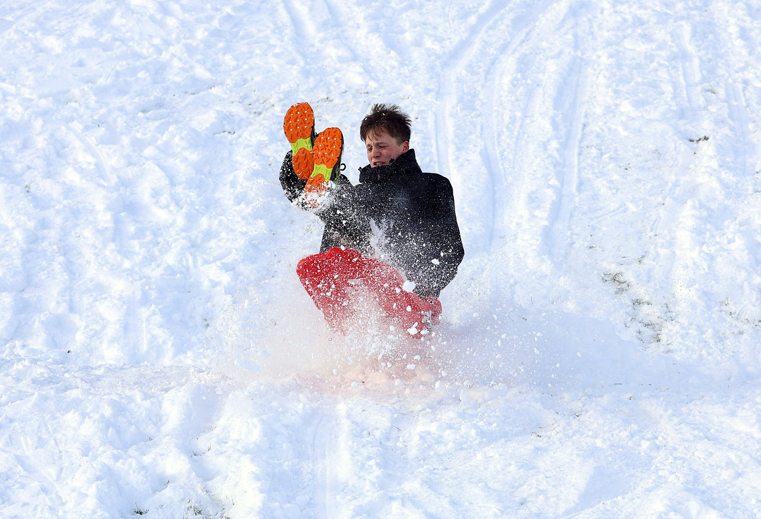 A youth sleighs in the snow, as cold weather warnings are extended into next week, in Glenariffe