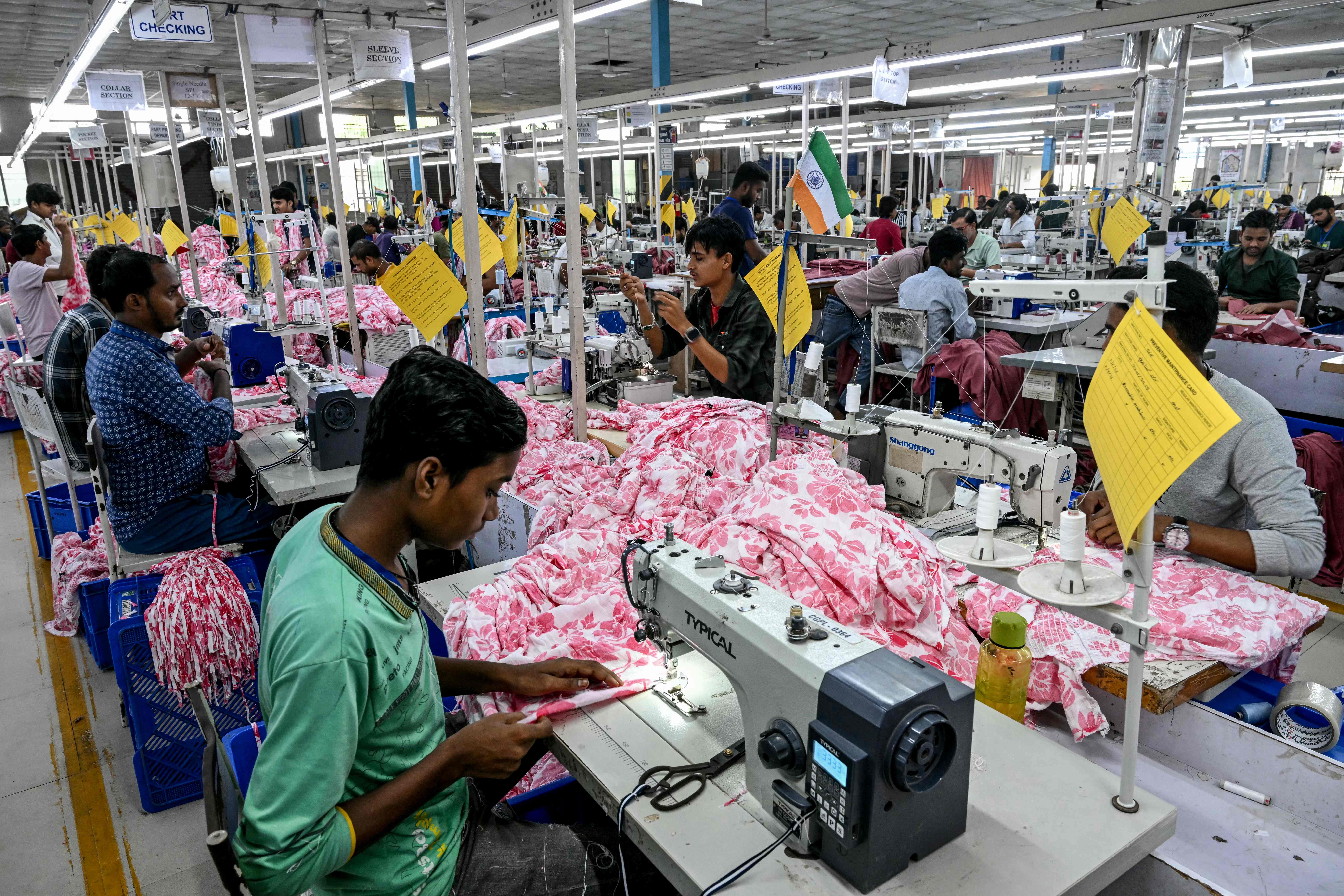 Employees stitch clothing material for dresses at the apparel manufacturing unit at Bhiwandi in the Thane district of India