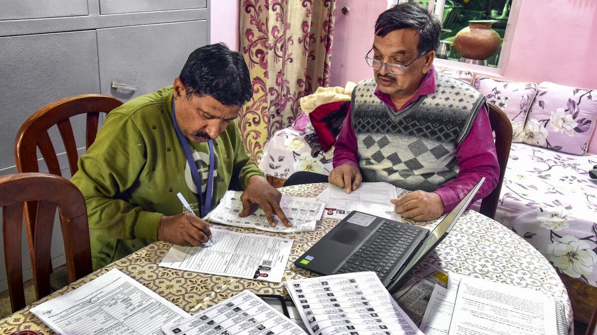 A booth level officer assisting a voter in filling out the enumeration form for the Special Intensive Revision of electoral rolls in Bikaner, Rajasthan. 