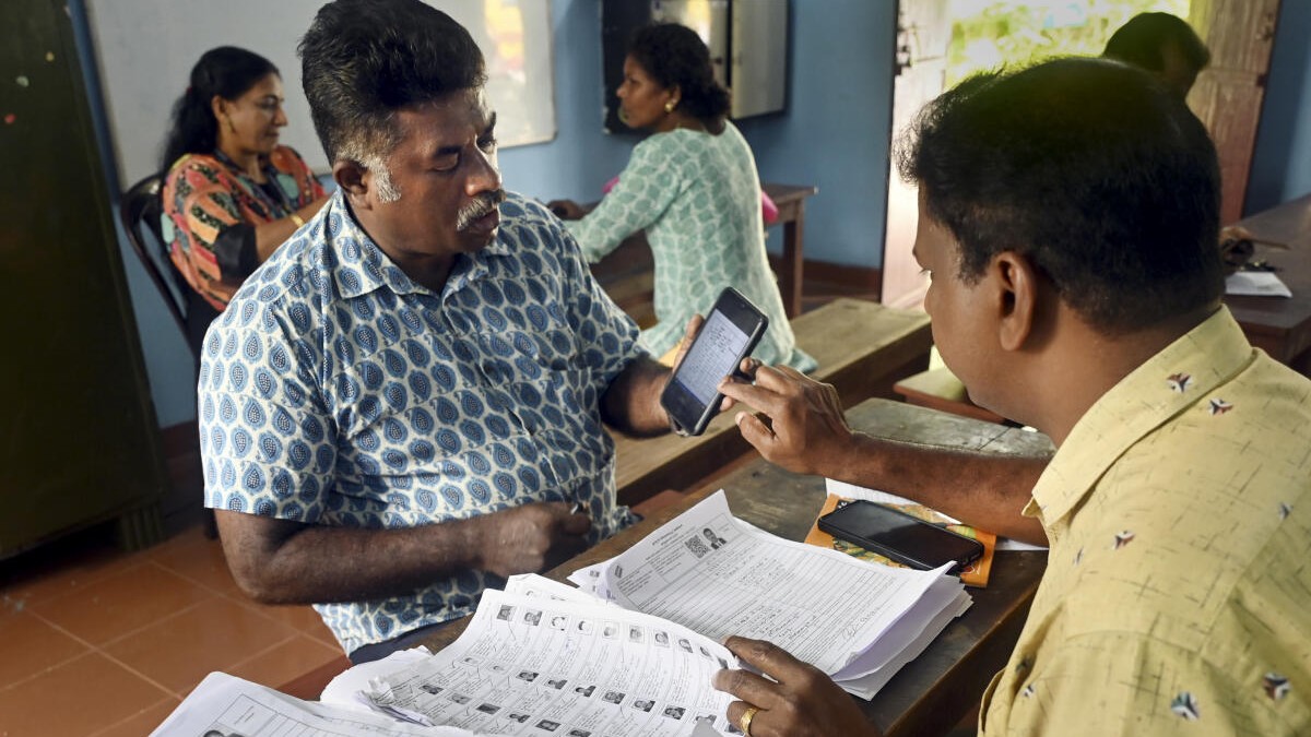 A booth level officer interacting with a voter as he checks and collects filled enumeration forms for the Special Intensive Revision of electoral rolls, in Thiruvananthapuram.