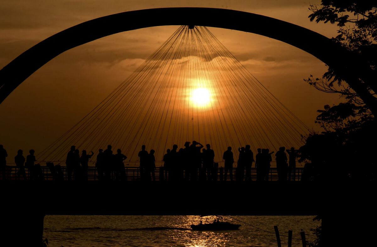 Visitors silhouetted against the setting sun, at Rainbow Hanging Bridge, in Kochi
