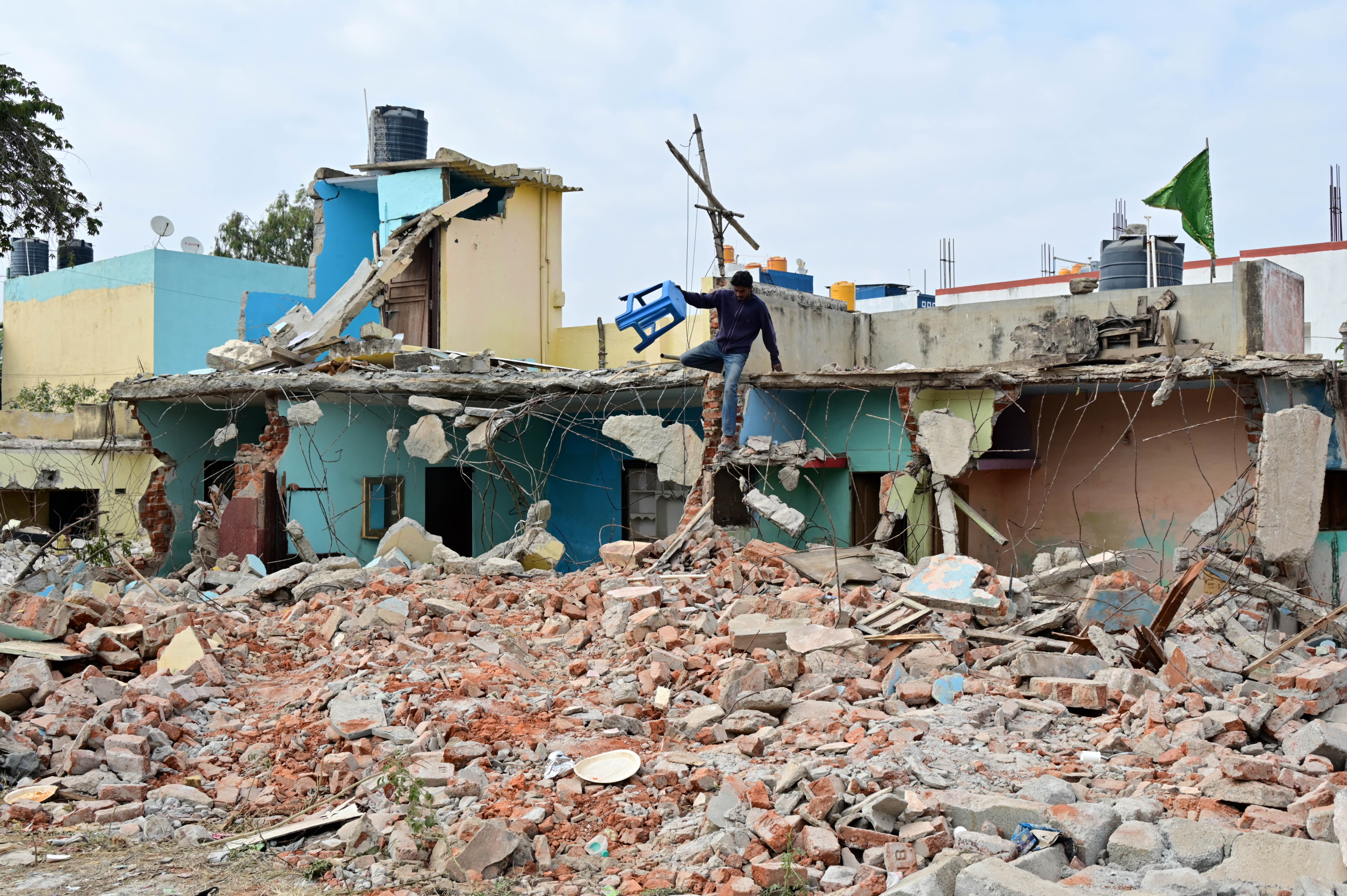Debris lies scattered as a man salvages belongings during the second day of the BDA’s encroachment removal drive at Thanisandra in Bengaluru on Friday. 