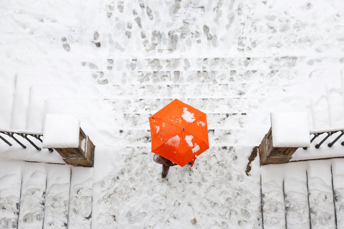 A woman walks down the snow-covered stairs near the medieval Charles Bridge during a snowfall in Prague, Czech Republic