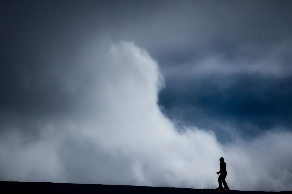 A skier stands on a ridge as clouds move, in Livigno, Italy
