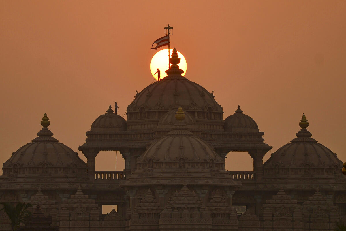 Workers carry out maintenance and beautification work atop the Akshardham Temple during sunset, in New Delhi