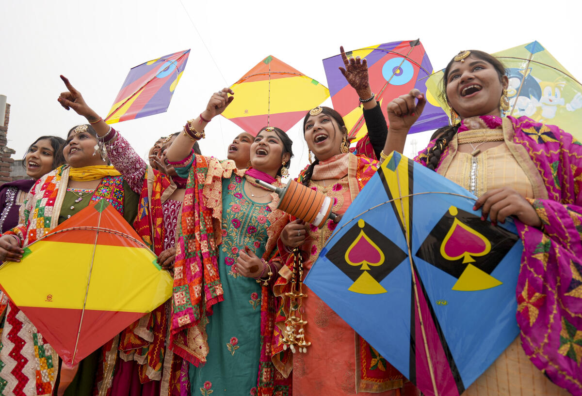 Women dressed in traditional attire hold kites ahead of the ‘Lohri’ festival celebrations, in Amritsar