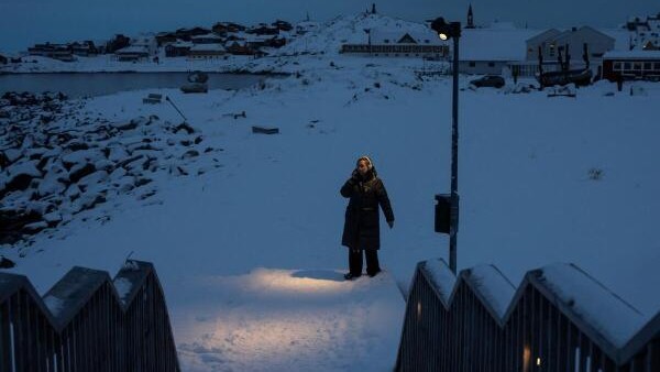 A woman walks by the sea at Nuuk's old harbour, Greenland.