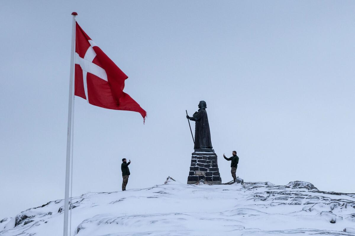 Danish soldiers take pictures next to the statue of Hans Egede, at Nuuk's old harbour, Greenland.