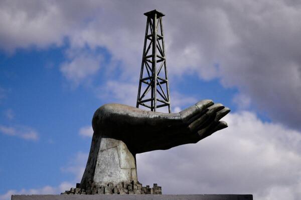 A structure of a hand holding an oil well tower stands near the headquarters of Venezuela's state-run oil company PDVSA, in Caraca.