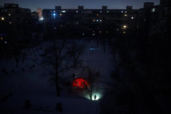 A person carrying a torch approaches a tent provided by emergency services for residents whose apartments are left without heating during sub-zero temperatures, amid Russia's attack on Ukraine, during a winter night in Kyiv, Ukraine.